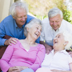 Group of senior friends sitting on garden seat laughing