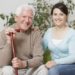 Smiling senior man holding cane and sitting with grandaughter