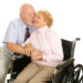 Affectionate senior husband giving his disabled wife a kiss on the cheek. Isolated on white.