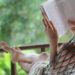 Woman lying in a hammock in a garden and enjoying a book reading